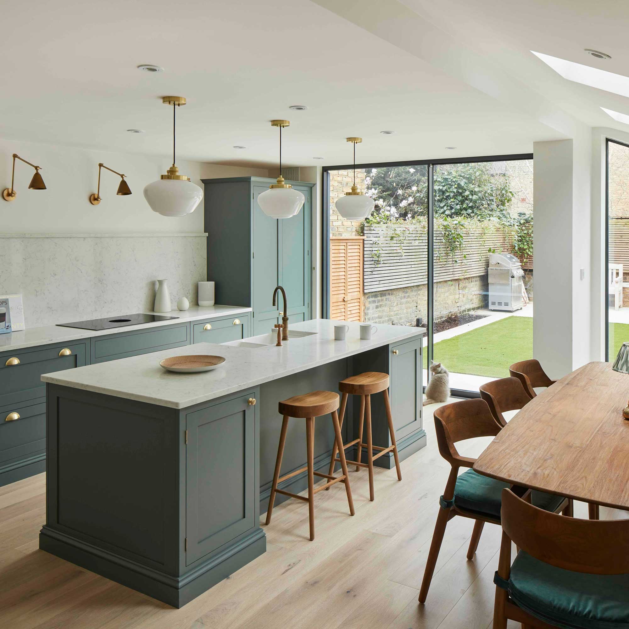 green Shaker kitchen with white worktops and sink