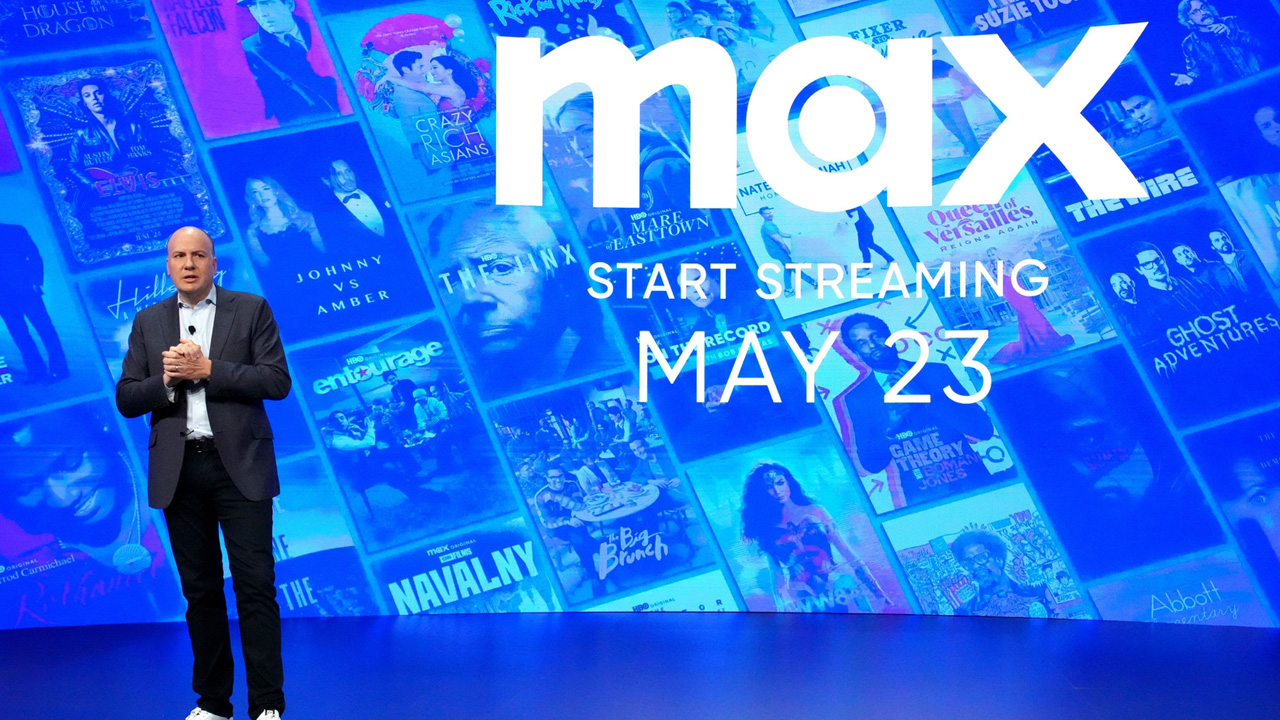 JB Perrette gives a talk standing in front of the Max logo on a big screen