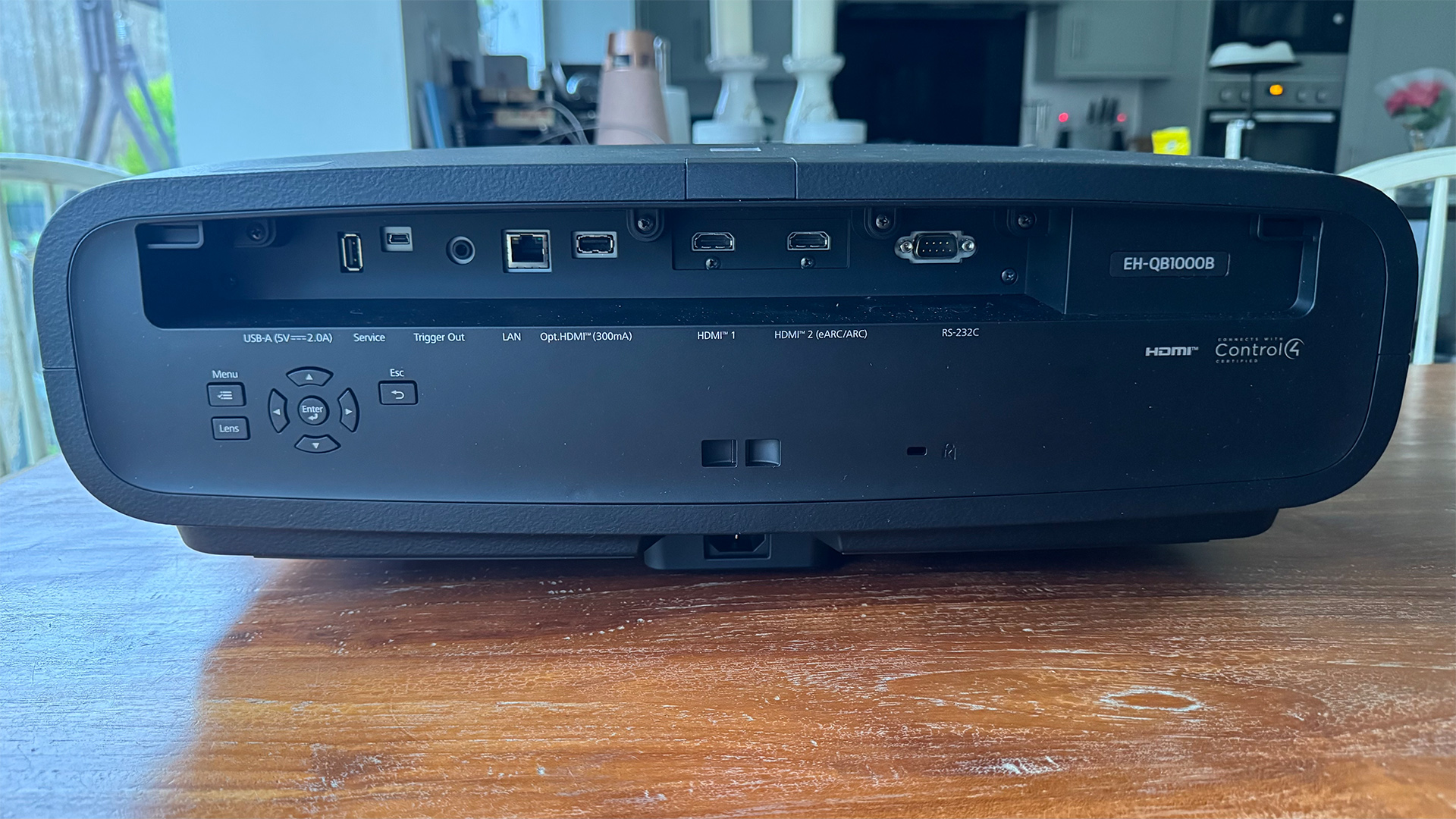 Epson EH-QB1000 home cinema projector on wooden table, rear of unit showing controls and connections