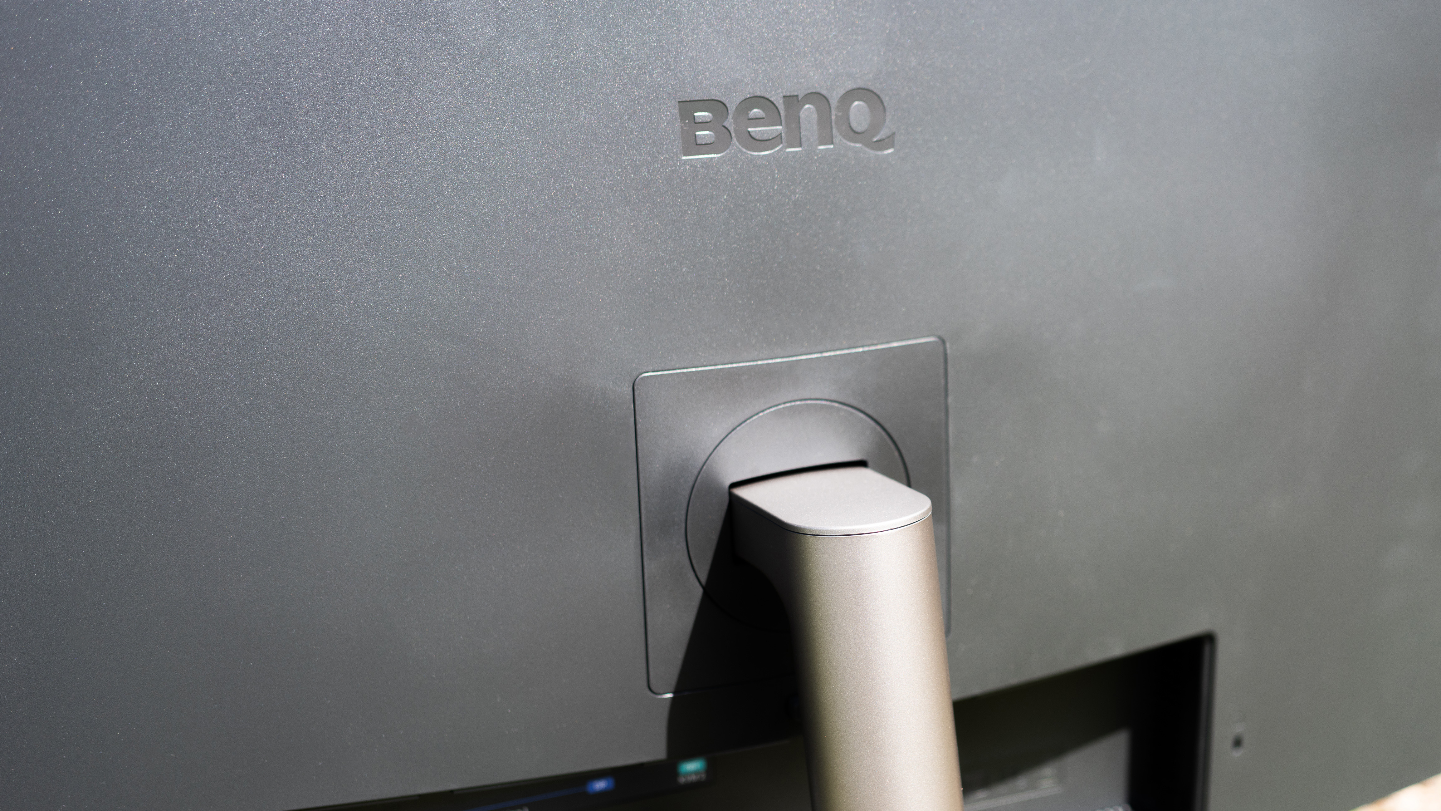 A black BenQ PD3225U monitor sitting on grass in sunshine