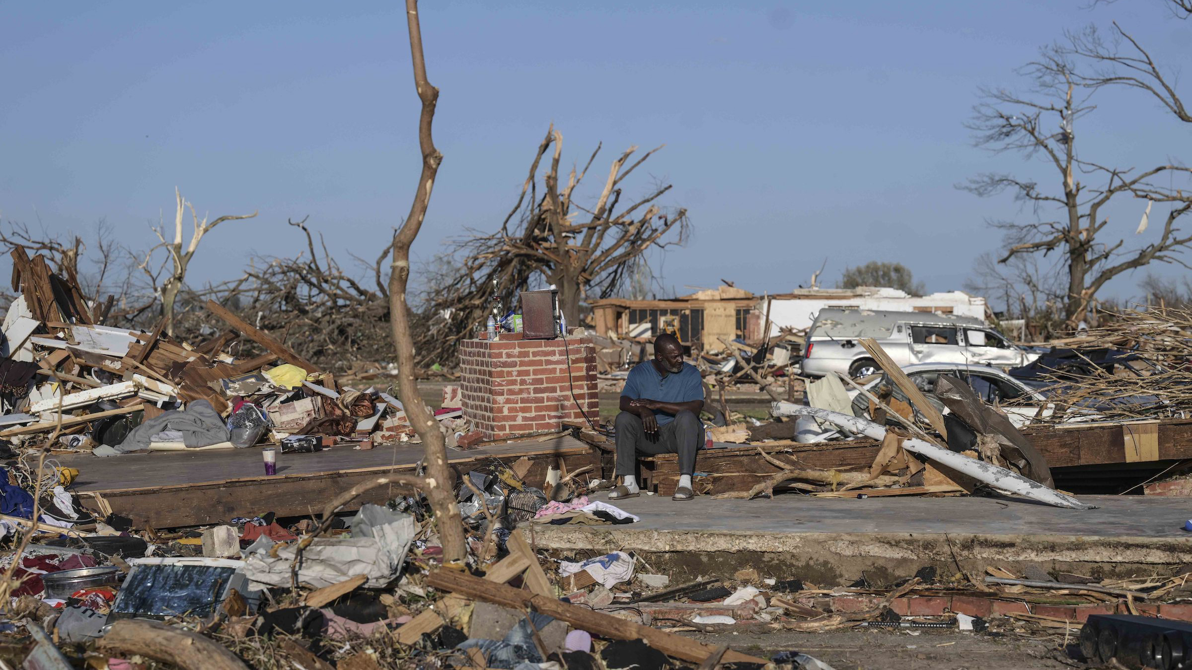 A man sits among the wreckage from a tornado that went through western Mississippi.
