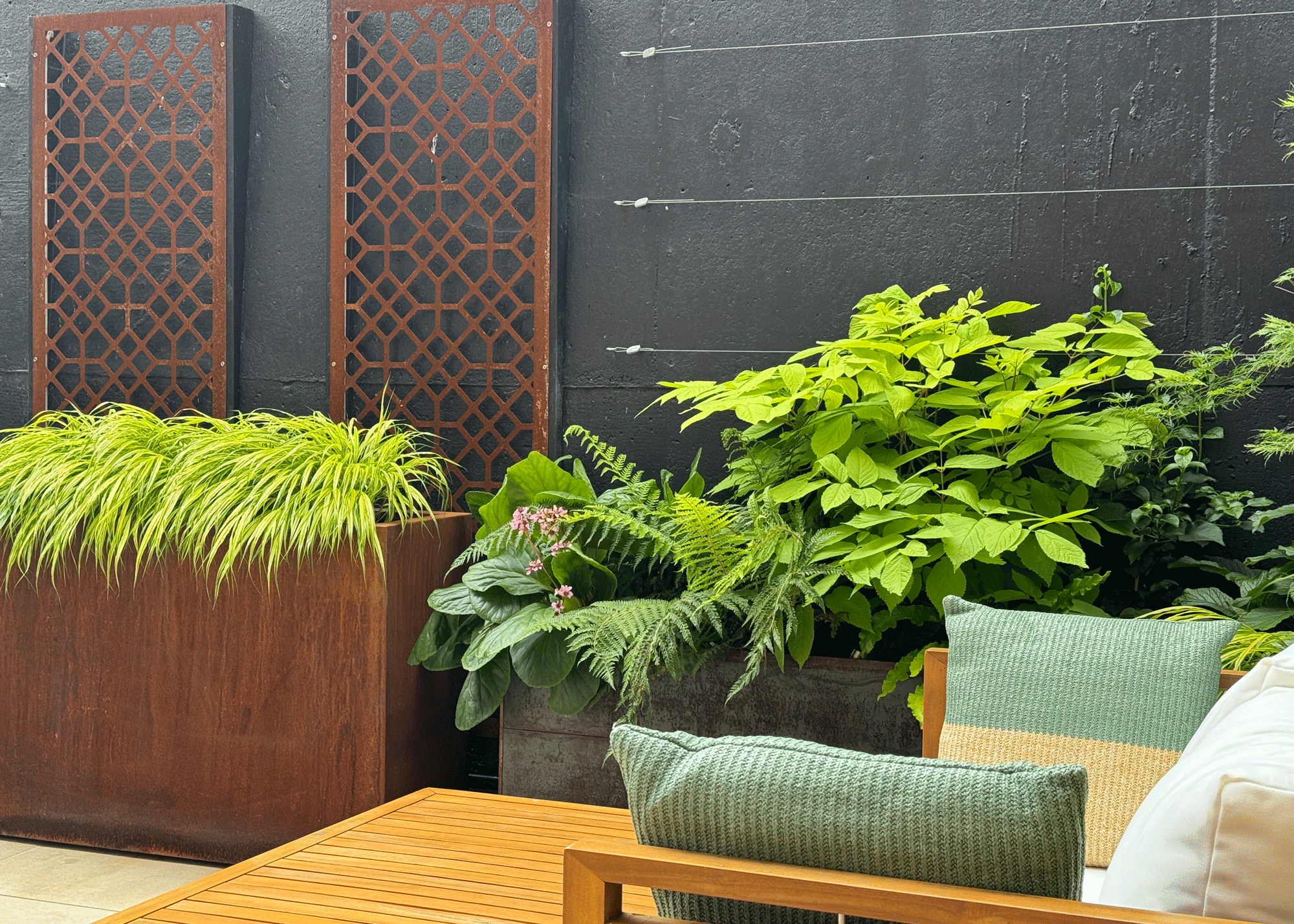 Patio with plants and furniture. on the patio chair are two cushions.