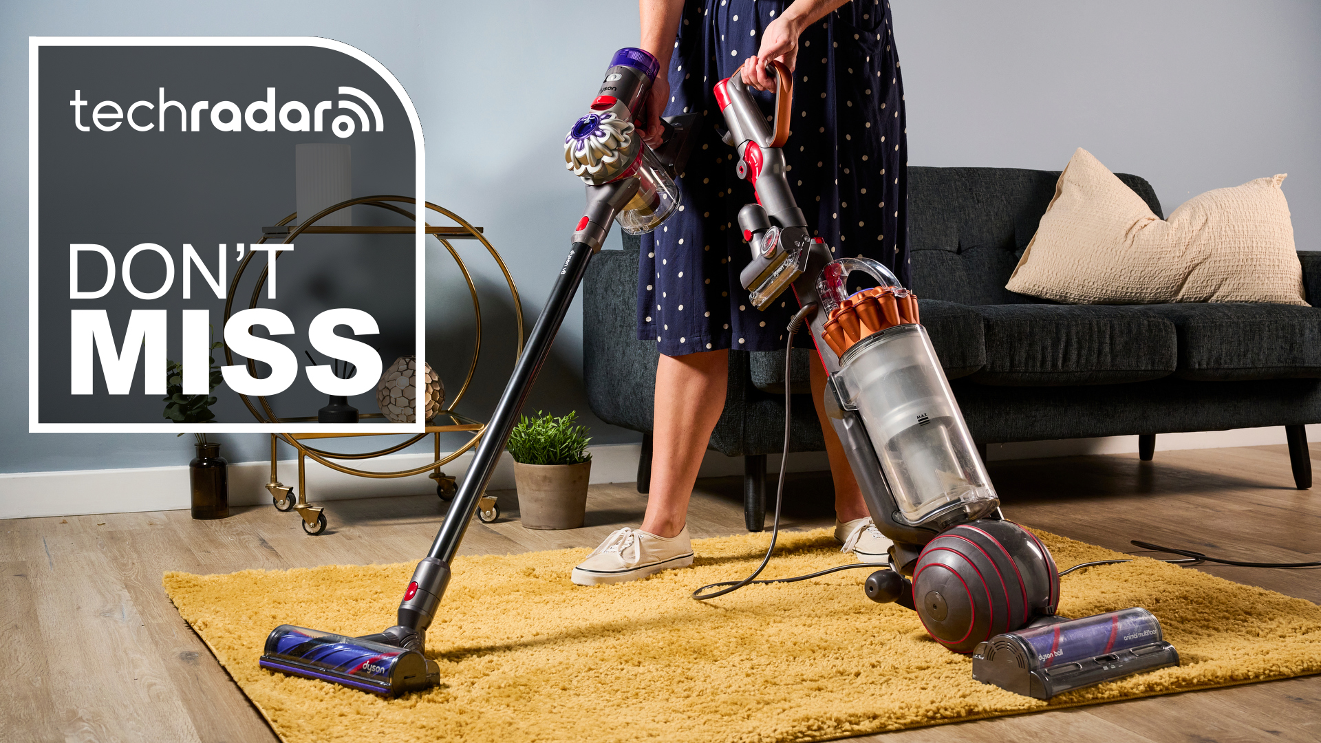 Woman holding a Dyson Ball Animal 3 vacuum and a V8 vacuum, with a sign saying Don't Miss