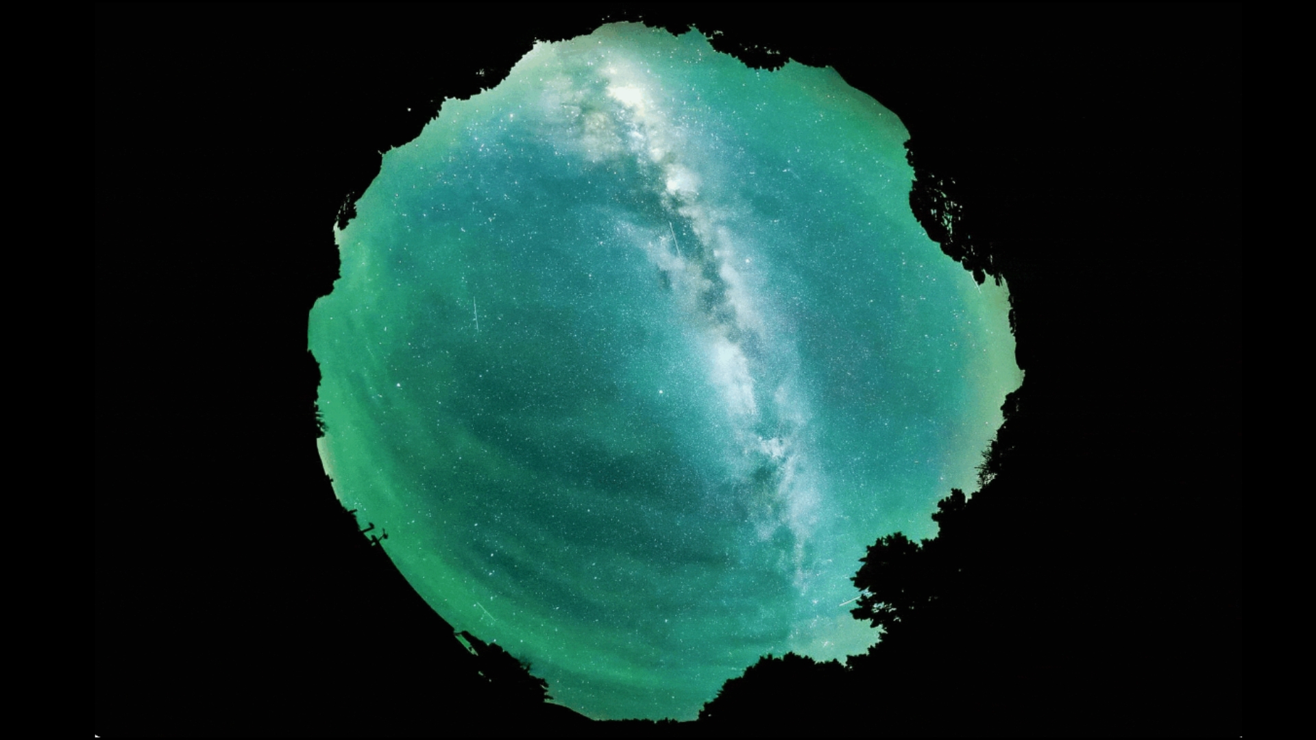 ripples move through a green hazy glow in the night sky with the bright milky way behind.