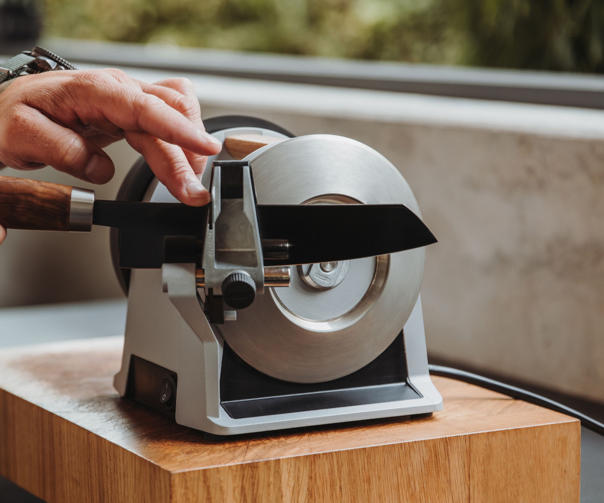 A Tormek knife sharpener sharpening a knife on a wooden board