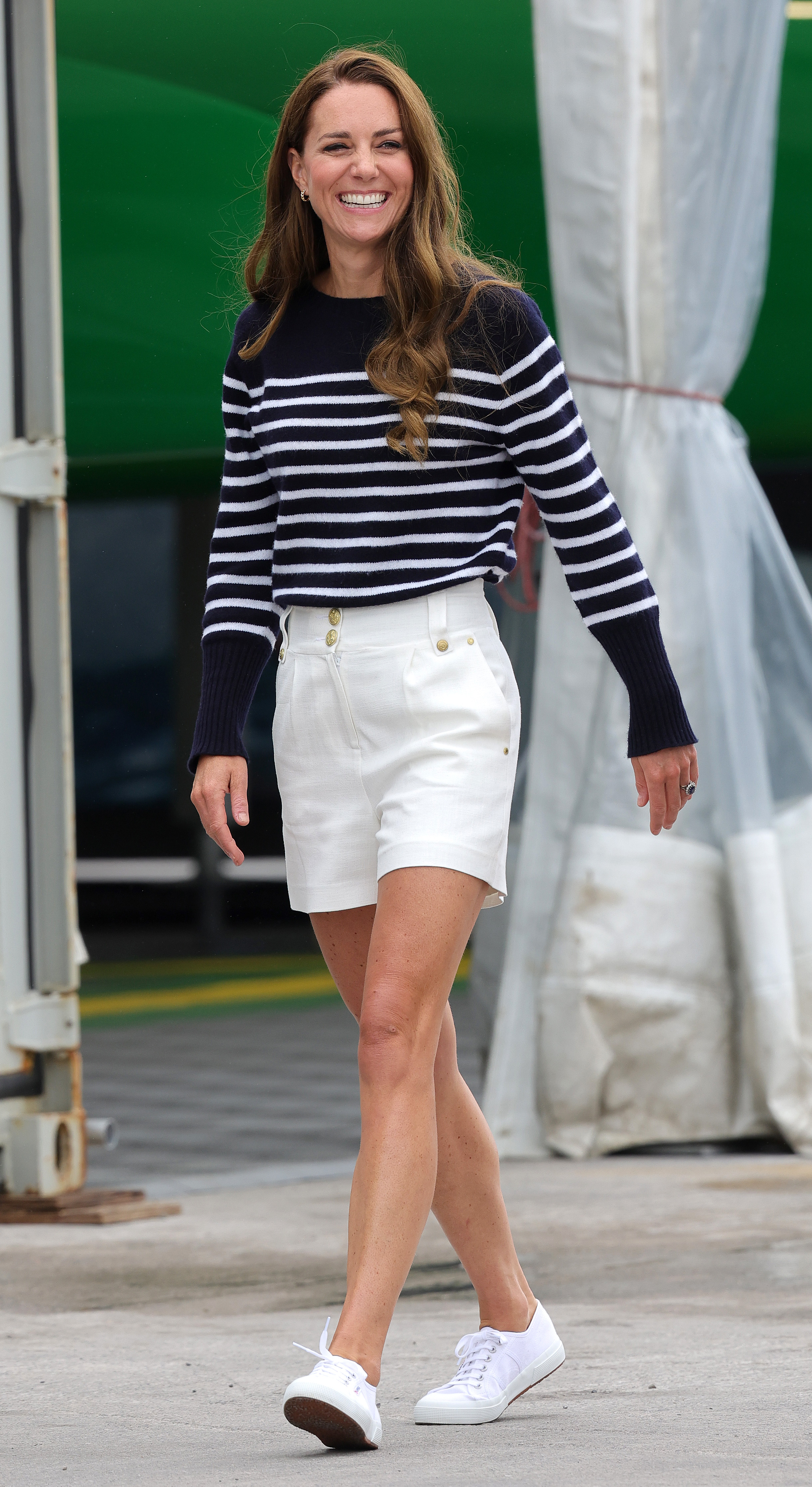 trendy sneaker brand, superga, is shown on a woman wearing white low top sneakers with white shorts and a navy striped sweater