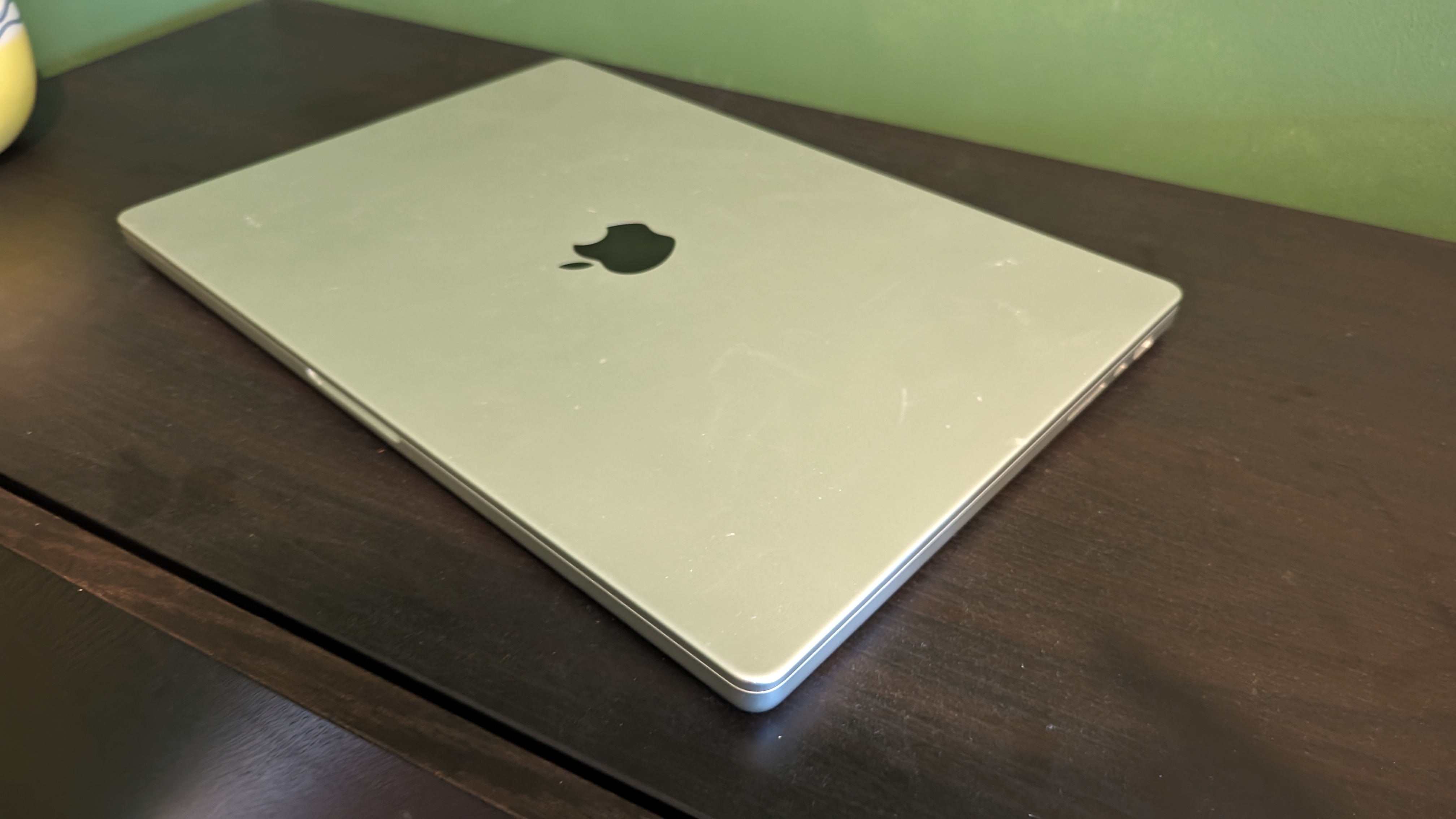 MacBook Pro 16-inch (2023) on wooden desk with green background
