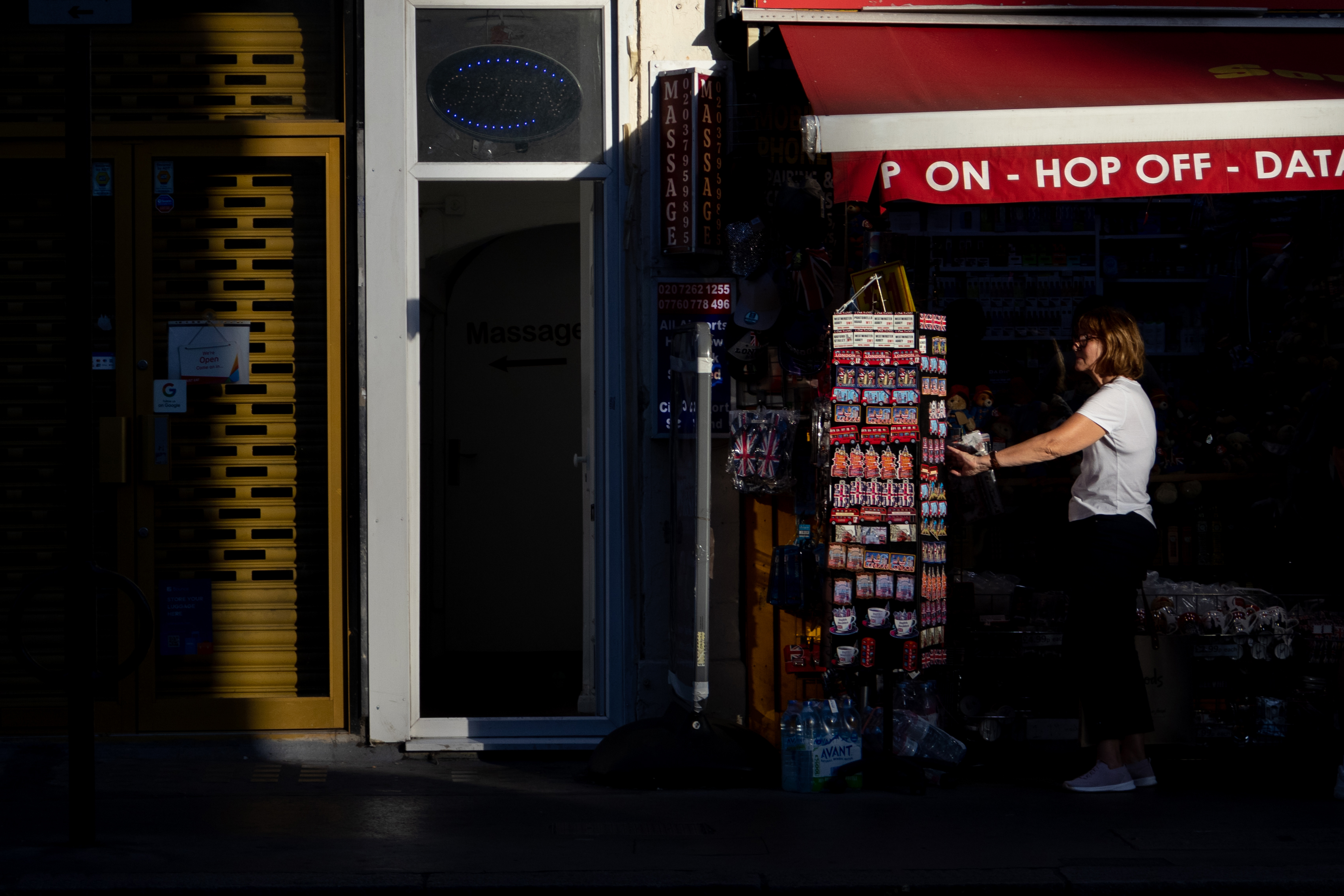 A woman looking at a rack of souvenirs outside a shop